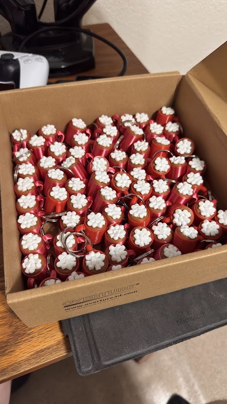 Red hot cocoa mug keychains with white marshmallow details.
